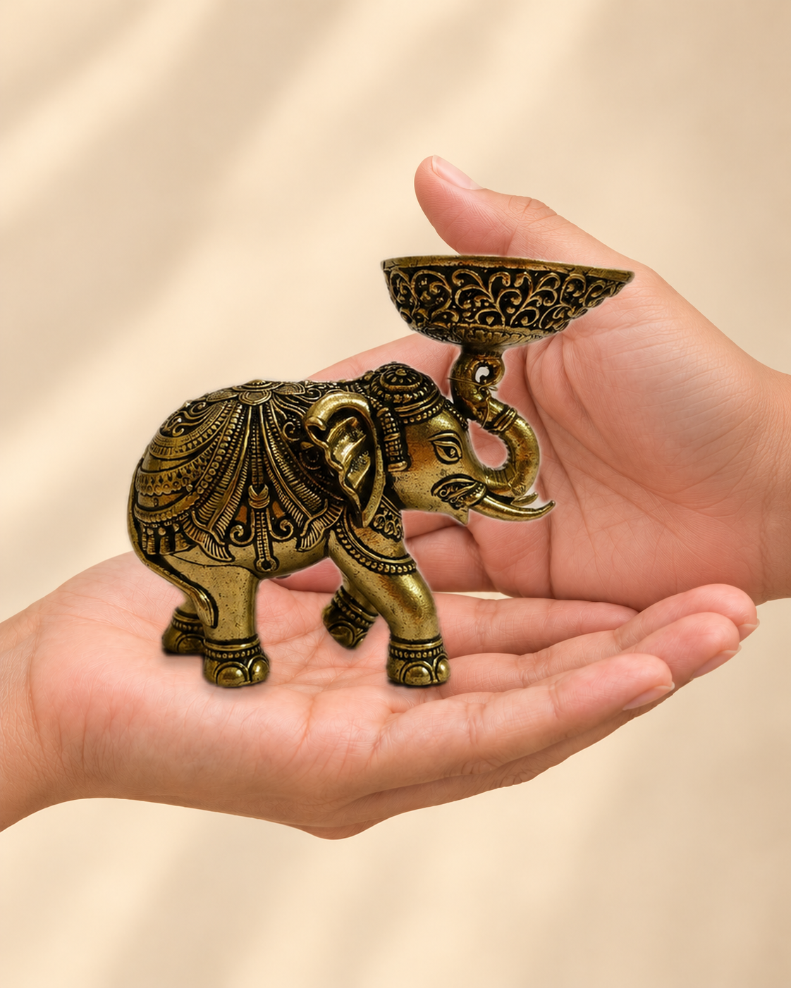 Illustrative scale view of Antique Brass Elephant Diya resting on an adult open palm; listed height 3.5 inches.