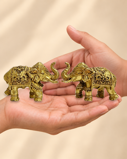 Illustrative scale view of Auspicious Brass Elephant Pair with Raised Trunks – 2 Inch resting on an adult open palm; listed height 2 inches.