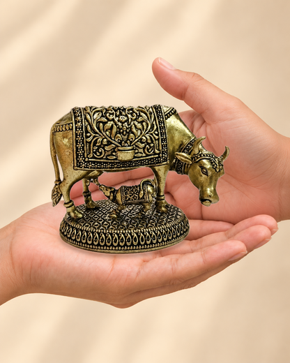 Illustrative scale view of Cow & Calf Brass Idol resting on an adult open palm; listed height 3.25 inches.