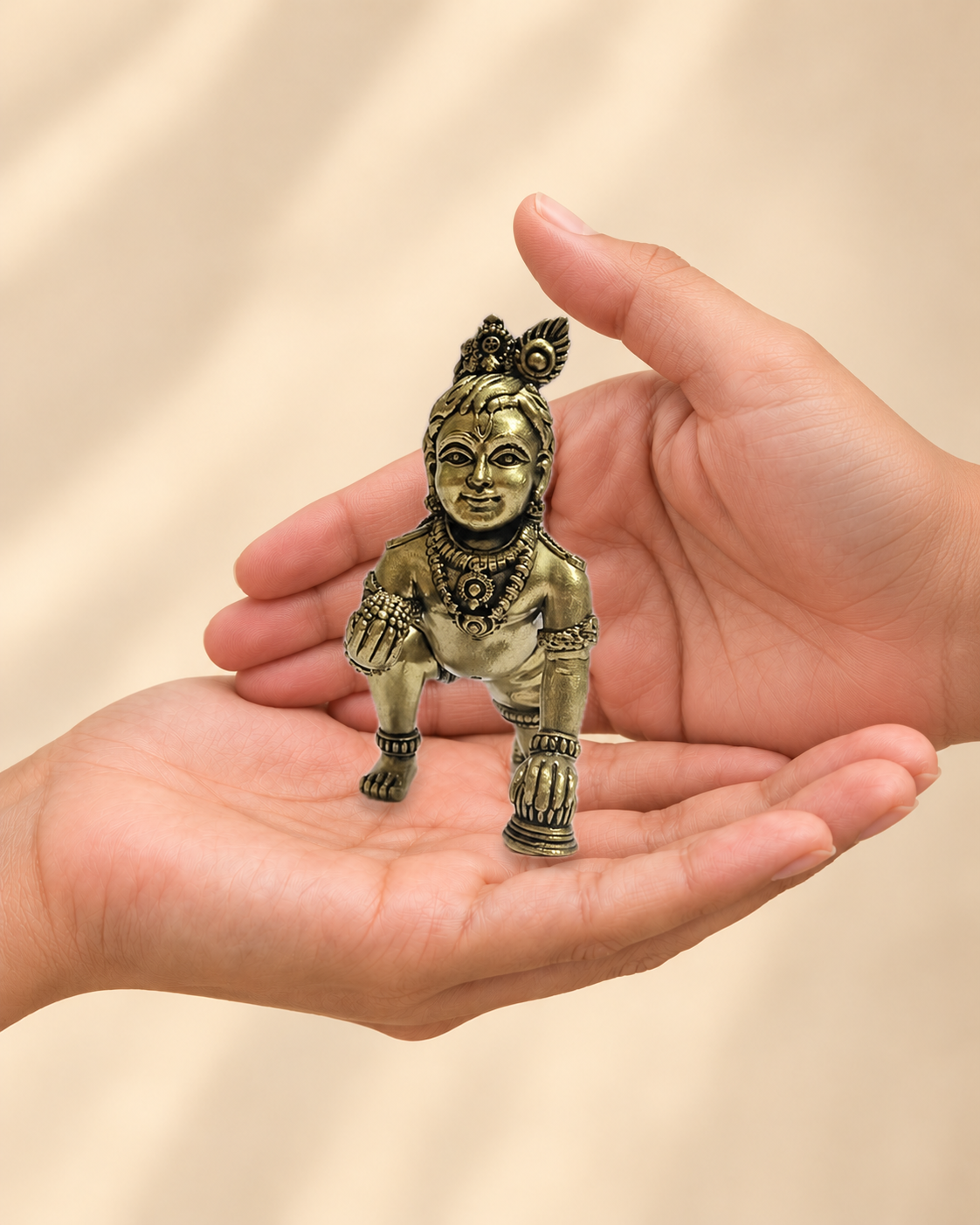 Illustrative scale view of Crawling Bal Krishna Brass Idol resting on an adult open palm; listed height 3.5 inches.