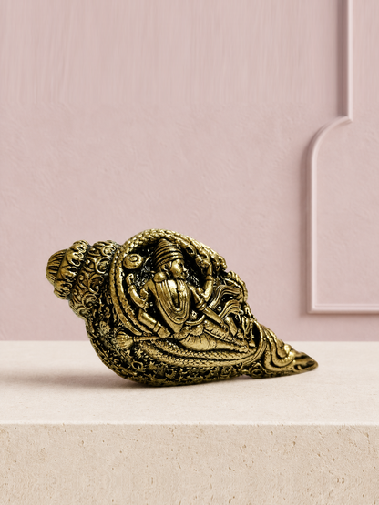 Decorative Brass Conch with Devotional Motifs on an ivory platform with a soft mauve heritage backdrop