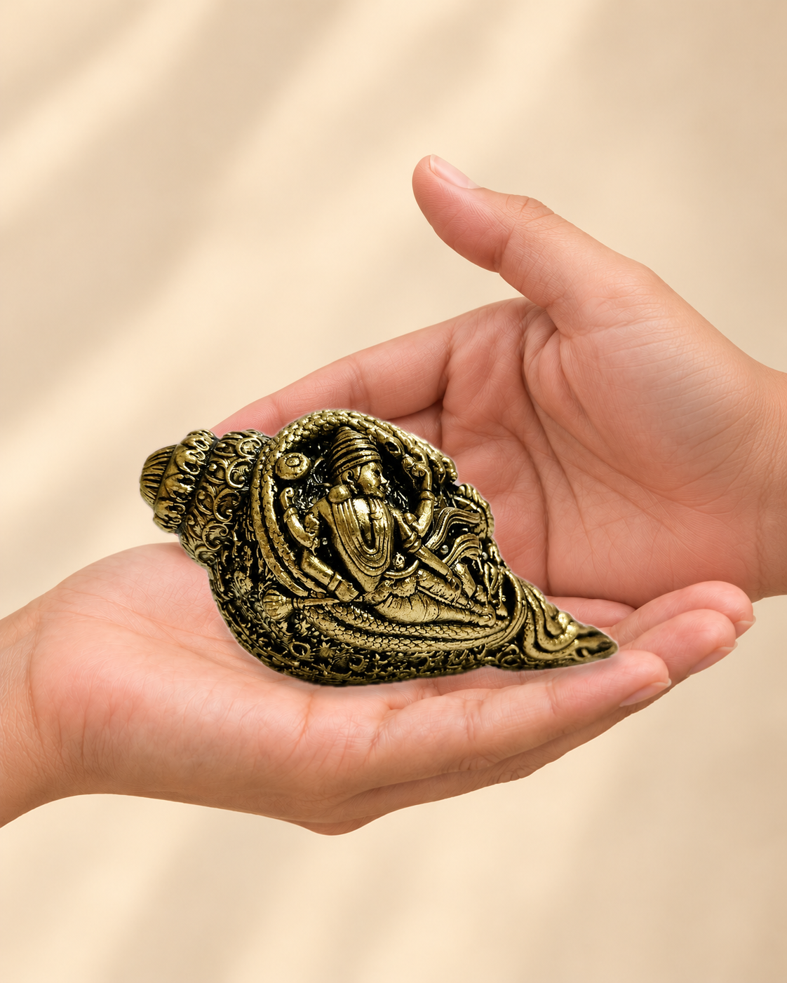 Illustrative scale view of Decorative Brass Conch With Devotional Motifs resting on an adult open palm; listed height 2.25 inches.