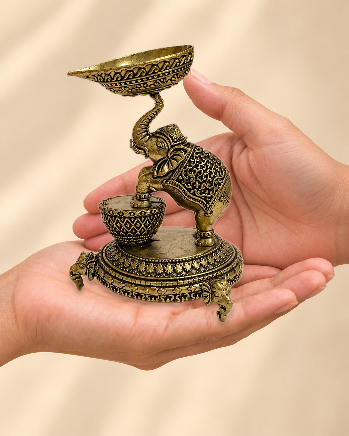 Illustrative scale view of Elephant Brass Diya resting on an adult open palm; listed height 5 inches.