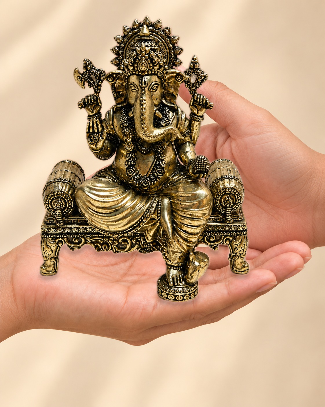Illustrative scale view of Ganesha Brass Idol On Ornate Throne resting on an adult open palm; listed height 5.5 inches.