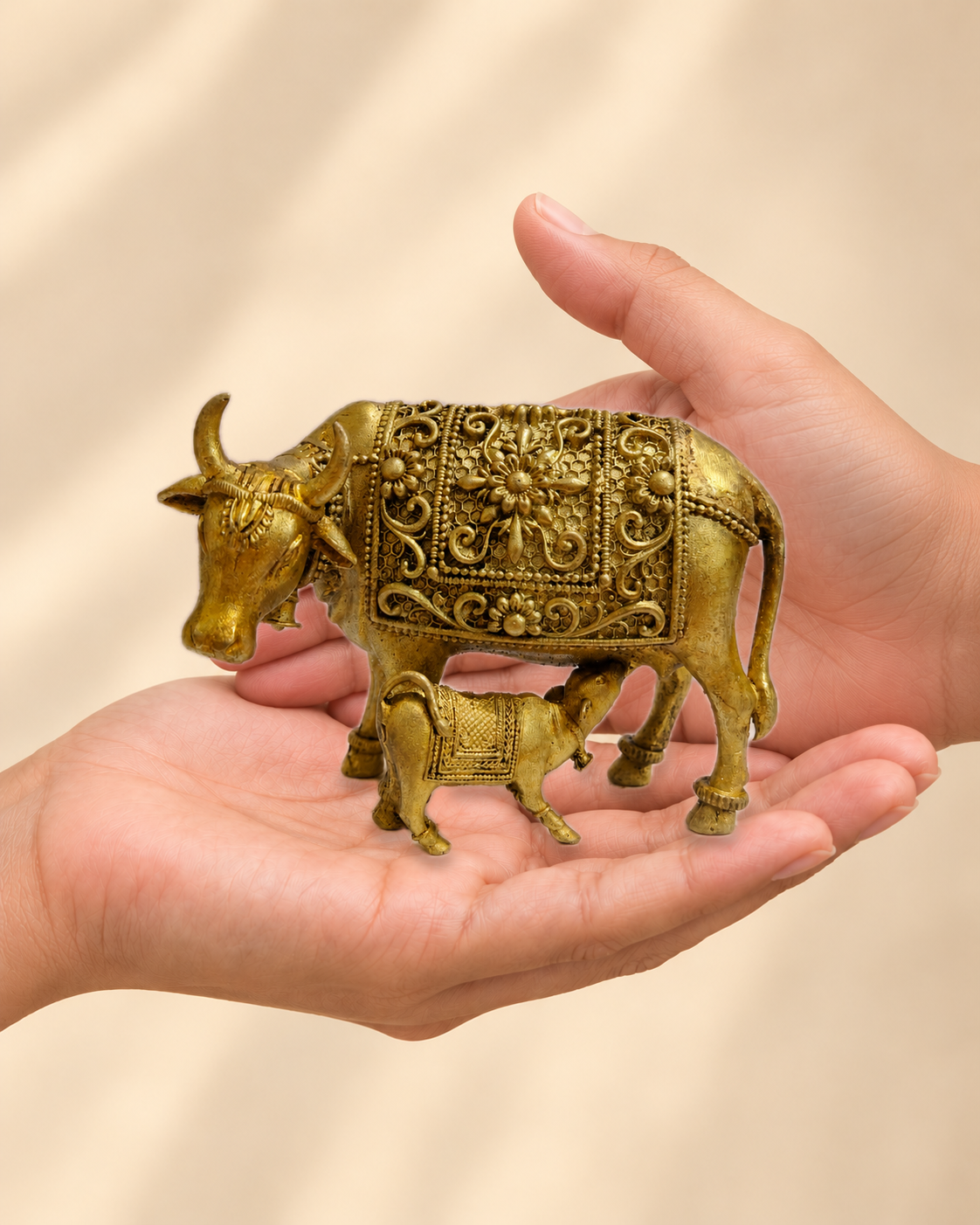 Illustrative scale view of Kamdhenu Cow and Calf Brass Idol resting on an adult open palm; listed height 3 inches.