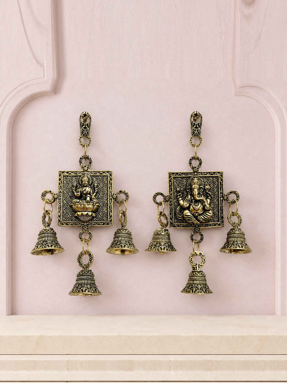 Lakshmi and Ganesha brass wall bell set displayed together on a soft mauve heritage wall