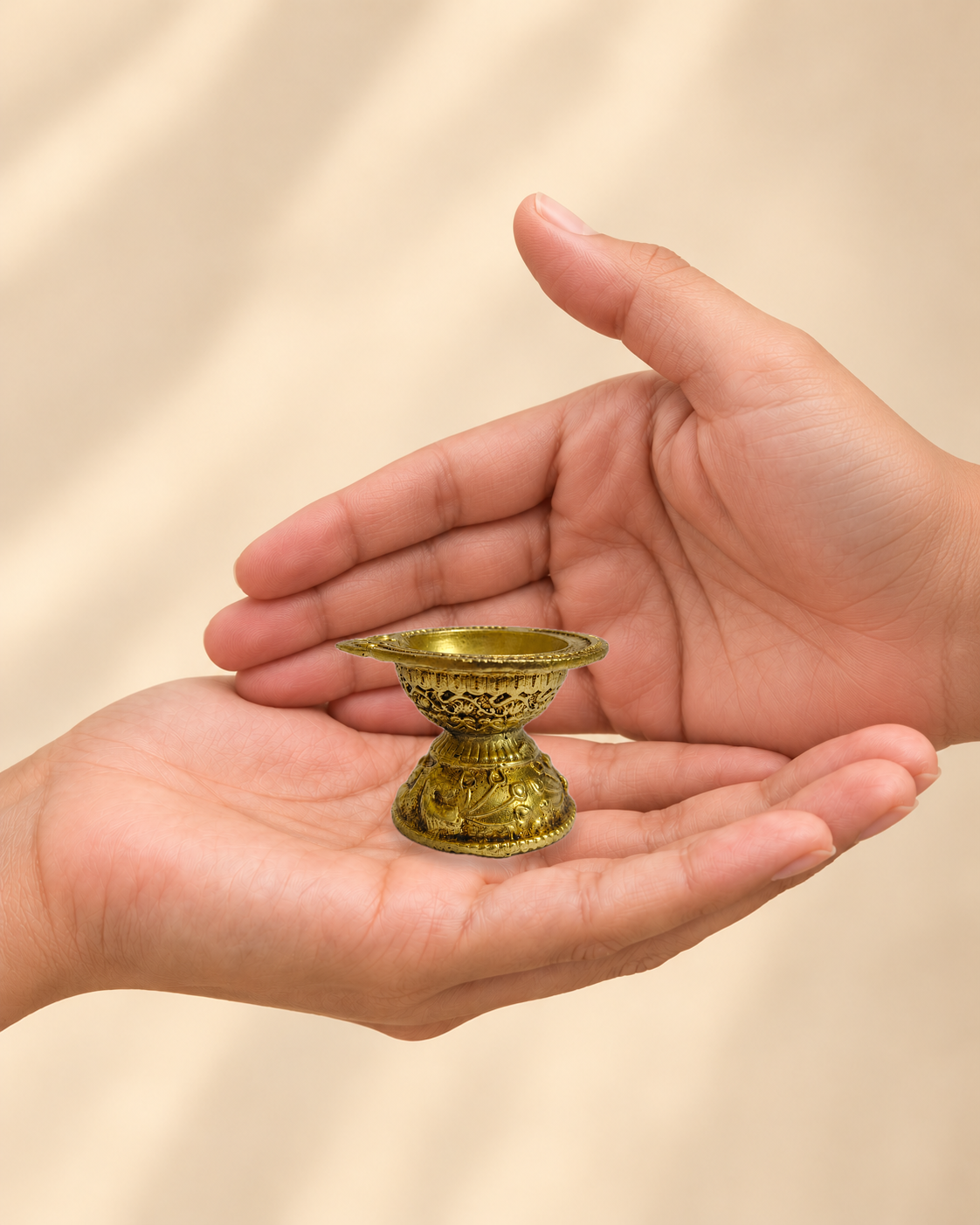 Illustrative scale view of Mini Pedestal Brass Diya resting on an adult open palm; listed height 1.5 inches.