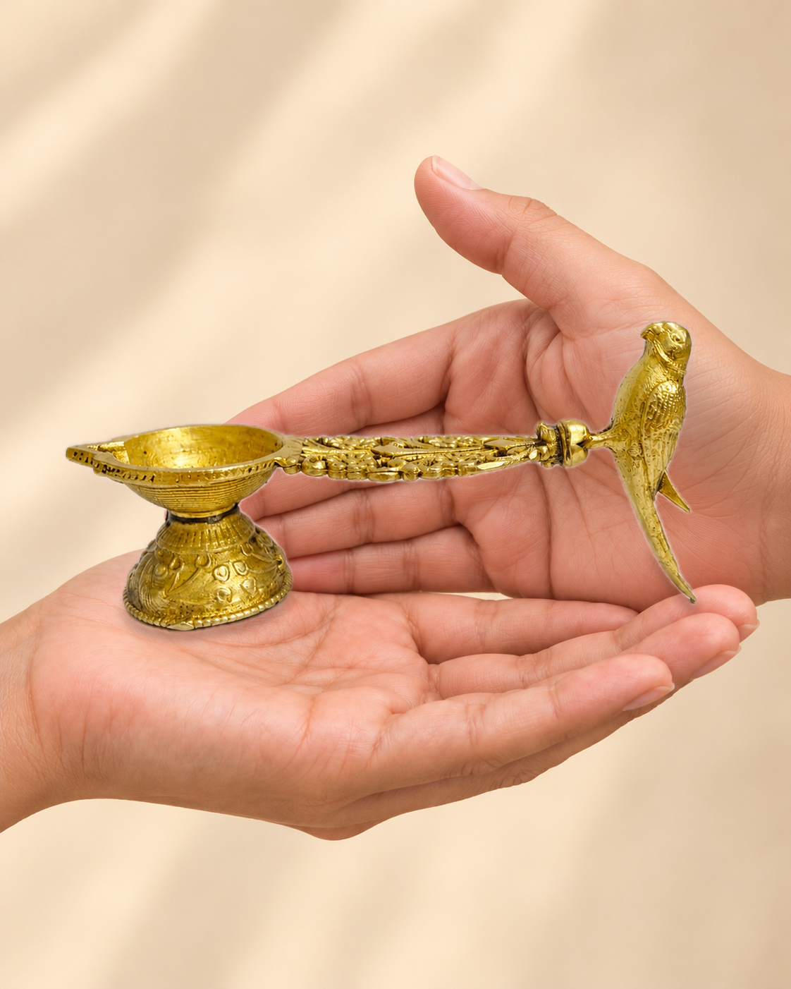 Illustrative scale view of Peacock Handle Brass Diya resting on an adult open palm; listed height 2.5 inches.