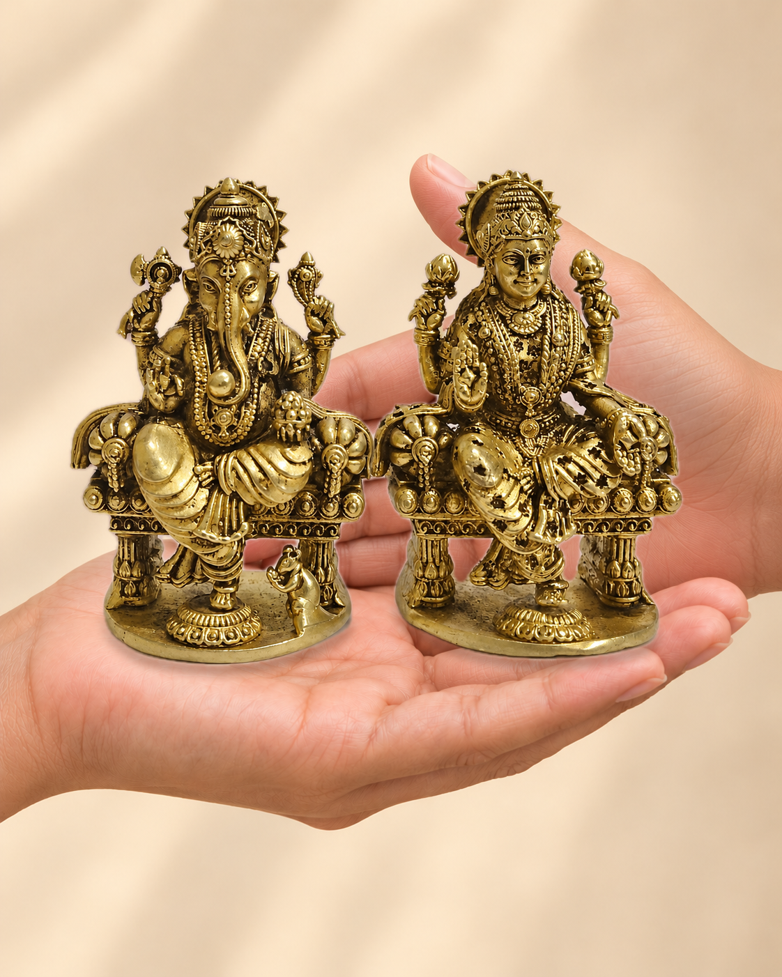 Illustrative scale view of Polished Brass Lakshmi Ganesha Idol Pair on Thrones – 4 Inch resting on an adult open palm; listed height 4 inches.
