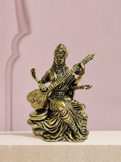 Saraswati Brass Idol with Veena on an ivory platform with a soft mauve heritage backdrop