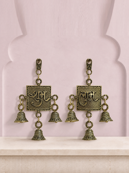 Shubh and Labh brass wall bell set displayed together on a soft mauve heritage wall
