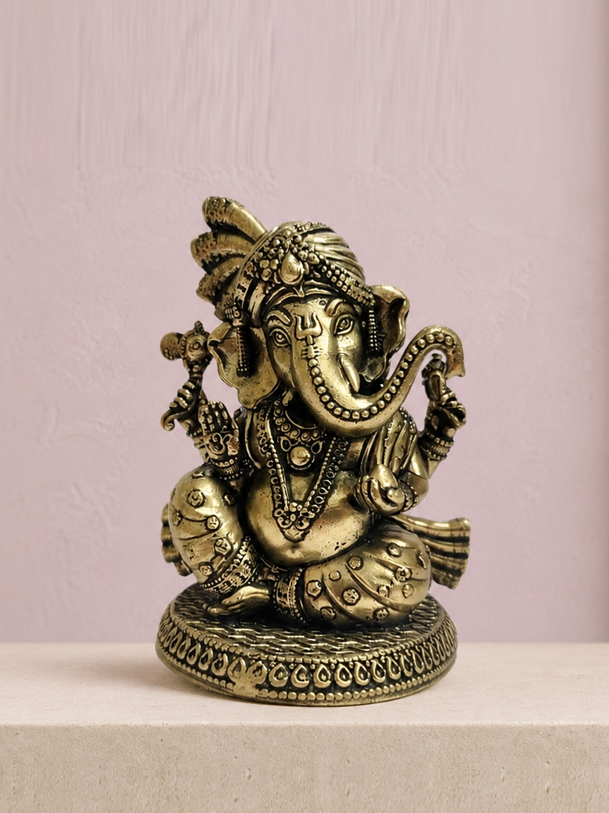 Turban Ganesha Brass Idol on an ivory platform with a soft mauve heritage backdrop