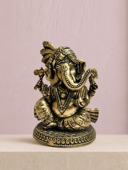 Turban Ganesha Brass Idol on an ivory platform with a soft mauve heritage backdrop