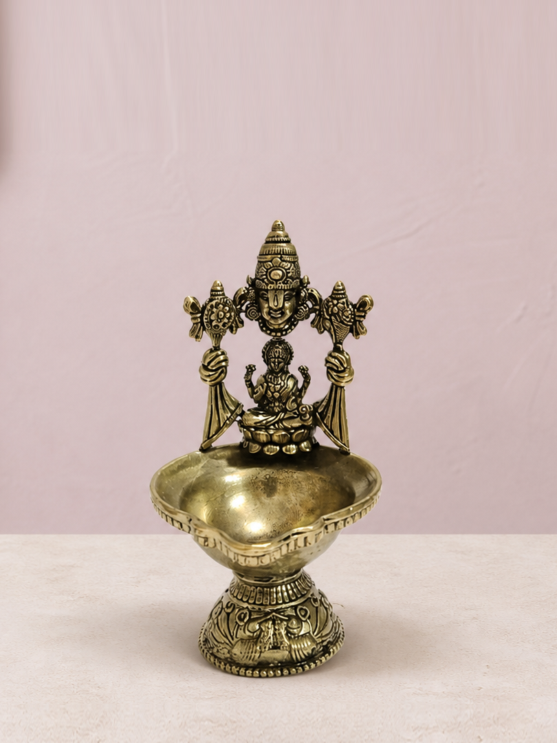 Venkateswara and Lakshmi Brass Diya Stand on an ivory platform with a soft mauve heritage backdrop